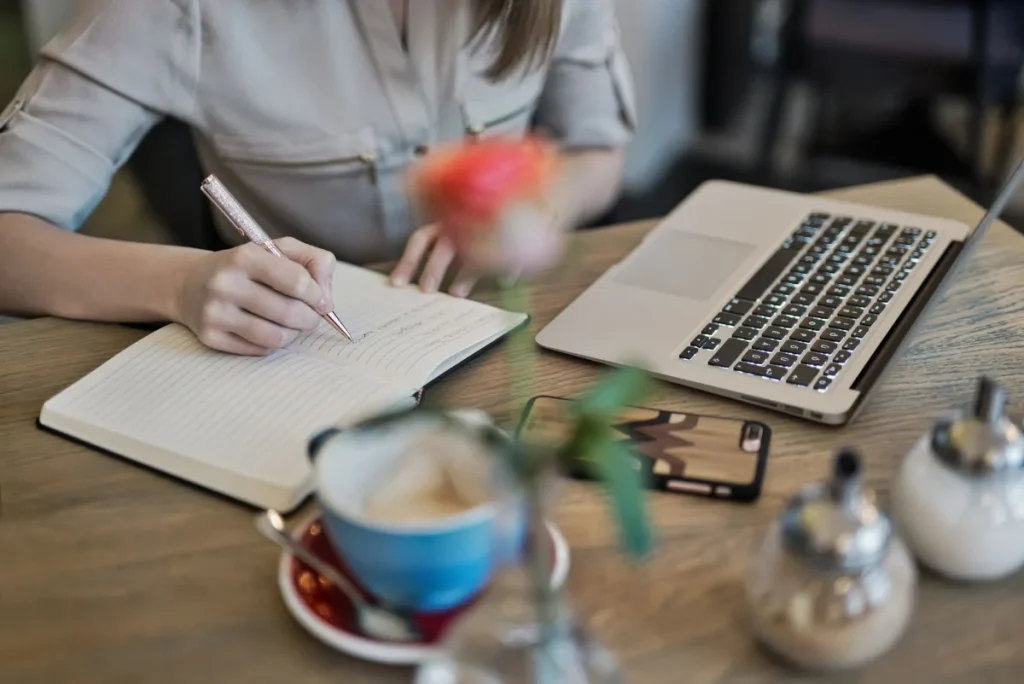 Penulis muda menyusun ide headline di meja kerja dengan laptop dan buku catatan