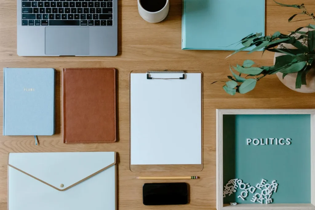 Meja kerja dengan laptop dan lembar contoh tulisan untuk menyusun portofolio copywriter