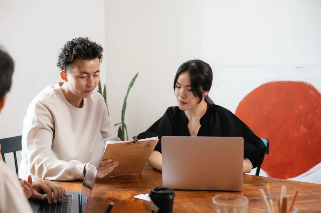 Copywriter dan klien membahas masukan draft bersama di depan laptop