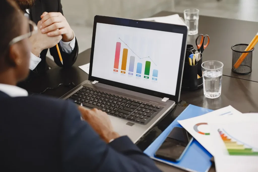 Pemasar mengevaluasi hasil kampanye iklan melalui grafik di laptop