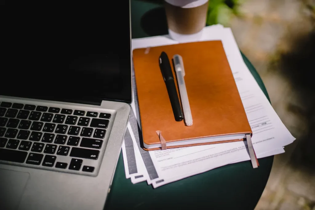 Meja kerja dengan laptop dan buku catatan untuk menyusun latihan copywriting