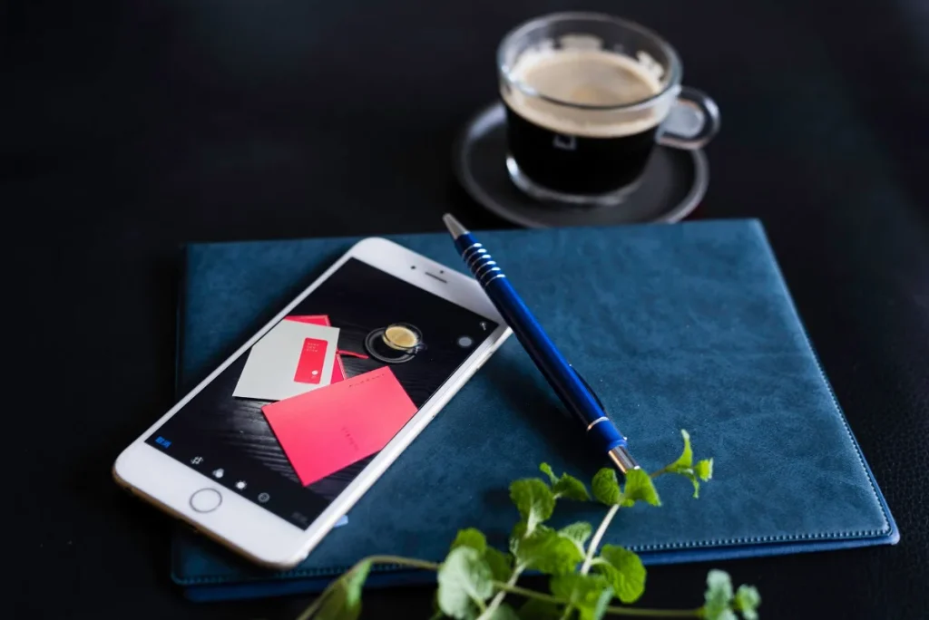 Seseorang menyusun alur caption Instagram dengan ponsel dan buku catatan