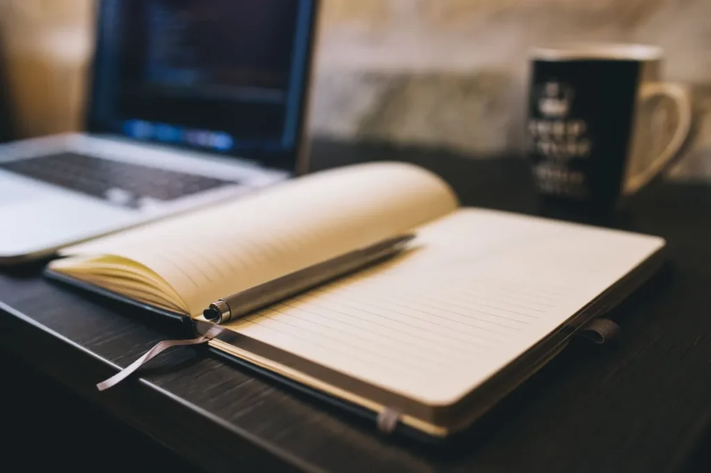 Profesional muda menyusun alur promosi di laptop dan buku catatan