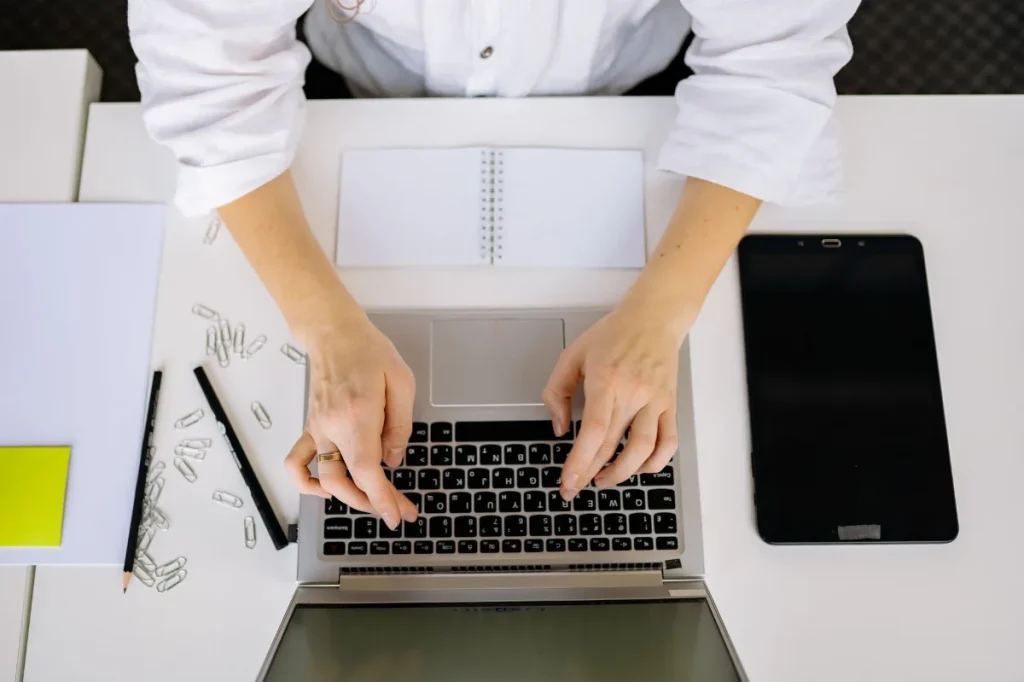 Copywriter menulis deskripsi produk di laptop dengan contoh produk di meja