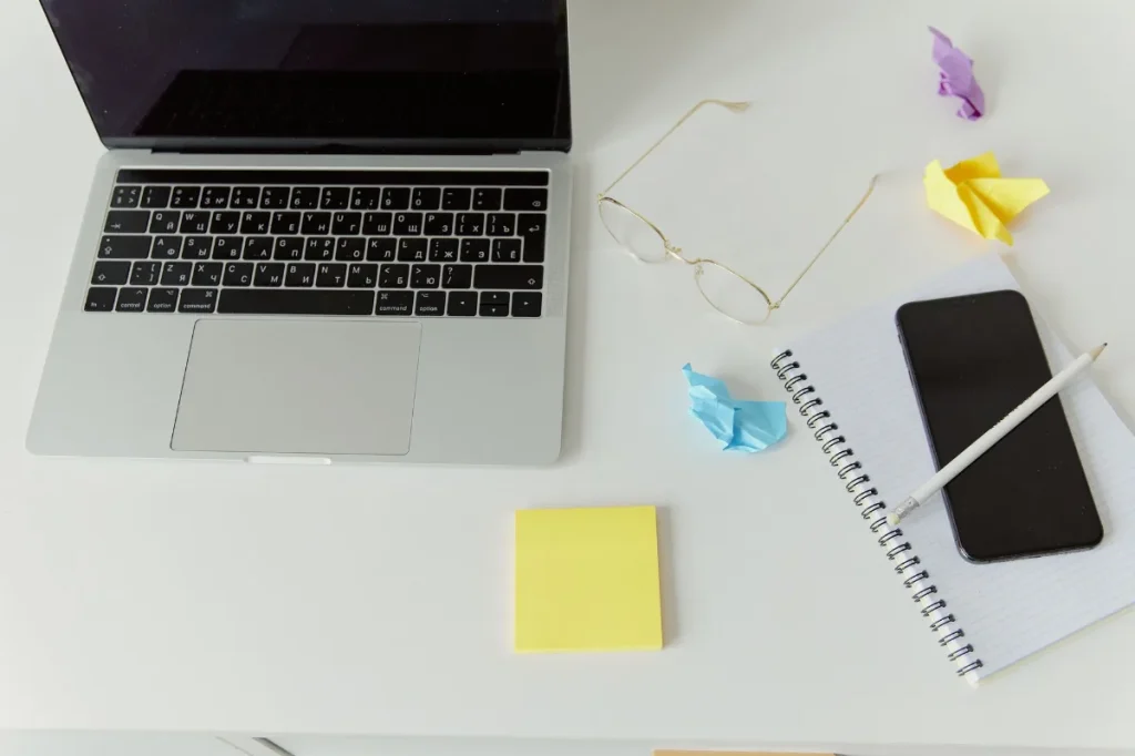 Copywriter menyusun konsep iklan di meja kerja dengan laptop dan kartu catatan
